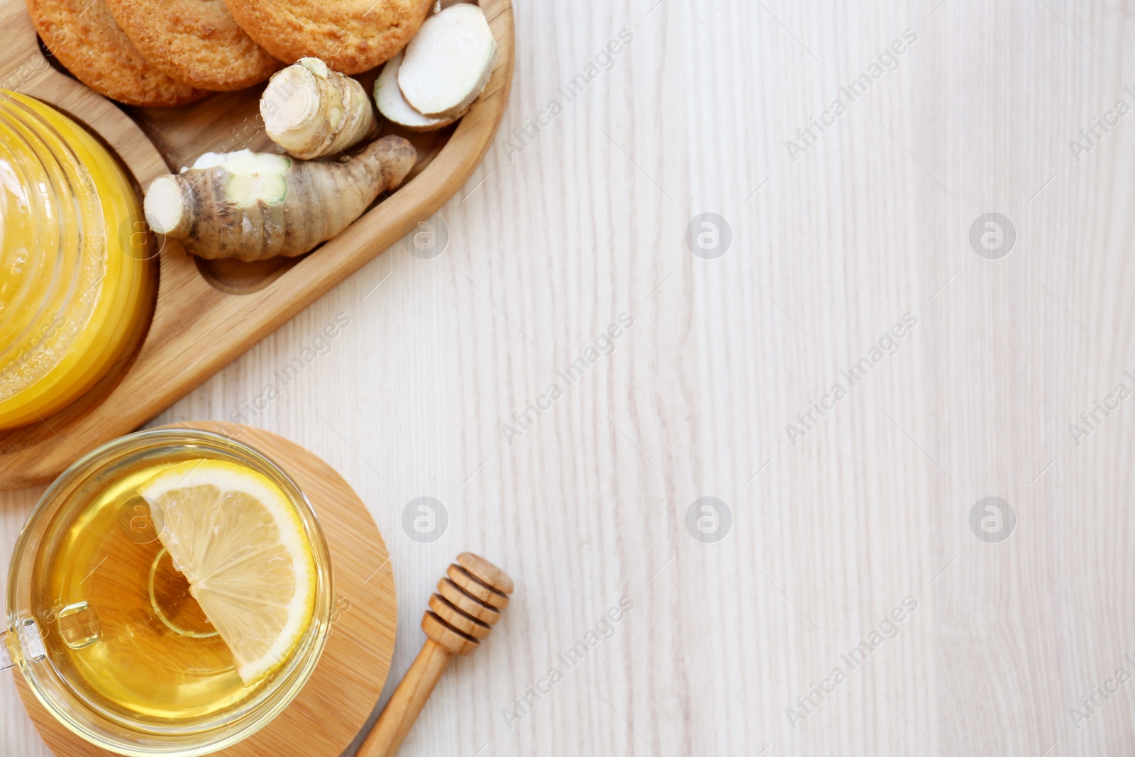 Photo of Cup of delicious tea with lemon, honey and ginger on white wooden table, flat lay. Space for text