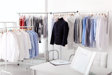 Photo of Dry-cleaner's interior with clothes on racks