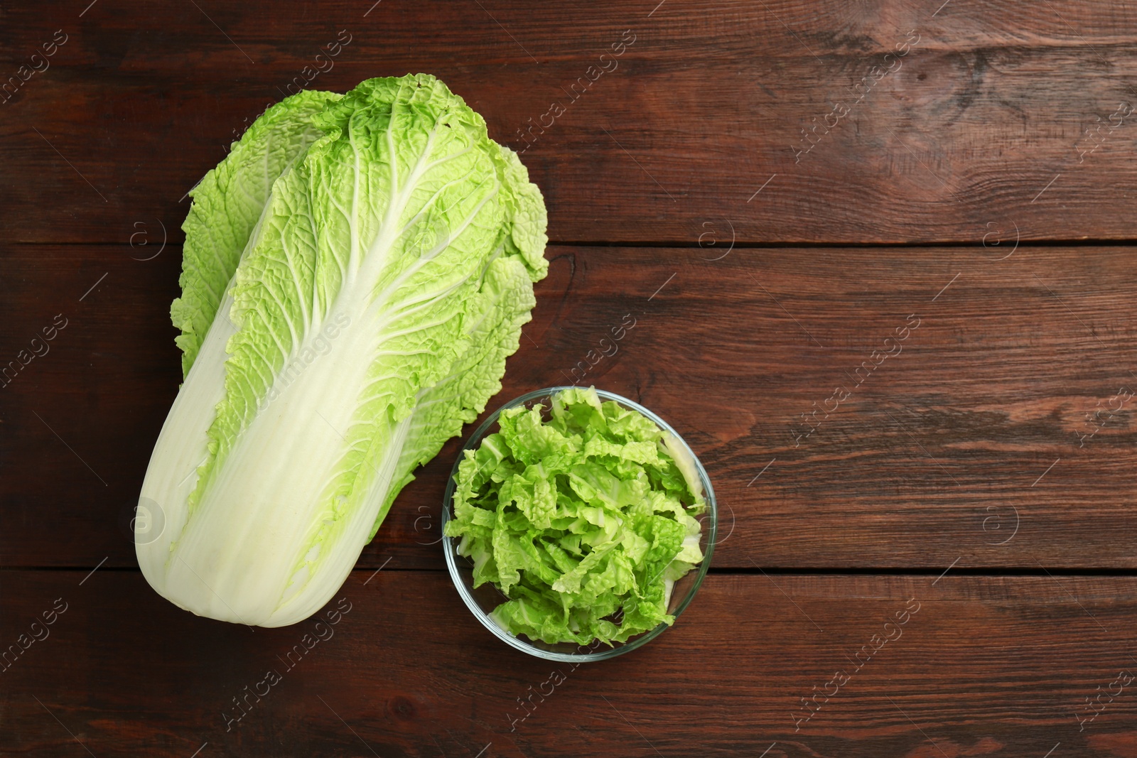 Photo of Whole and cut fresh Chinese cabbage on wooden table, top view. Space for text