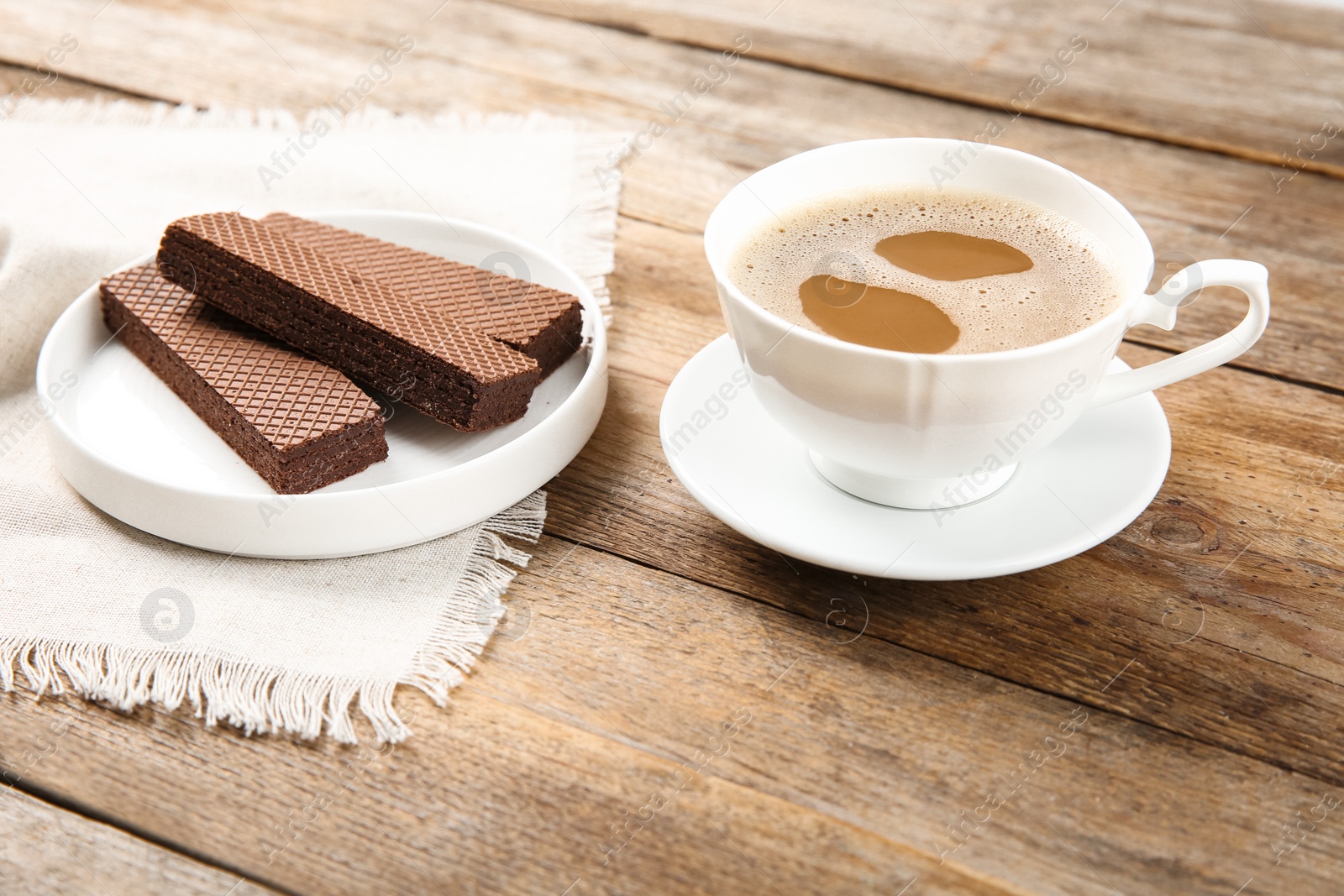 Photo of Plate of delicious chocolate wafers with cup of coffee on brown wooden background