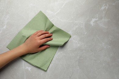 Photo of Woman cleaning light grey table with paper towel, top view. Space for text