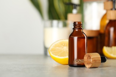 Photo of Bottle of #essential oil, pipette and lemon on light grey table, space for text