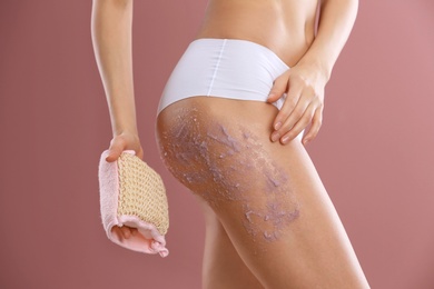 Photo of Young woman applying natural scrub on her body against color background