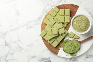 Photo of Pieces of tasty matcha chocolate bar and powder on white marble table, top view. Space for text