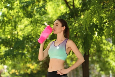 Photo of Athletic young woman drinking protein shake at green park