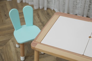 Photo of Small table and chair with bunny ears in children's room