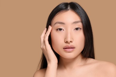 Portrait of beautiful young Asian woman on beige background, space for text