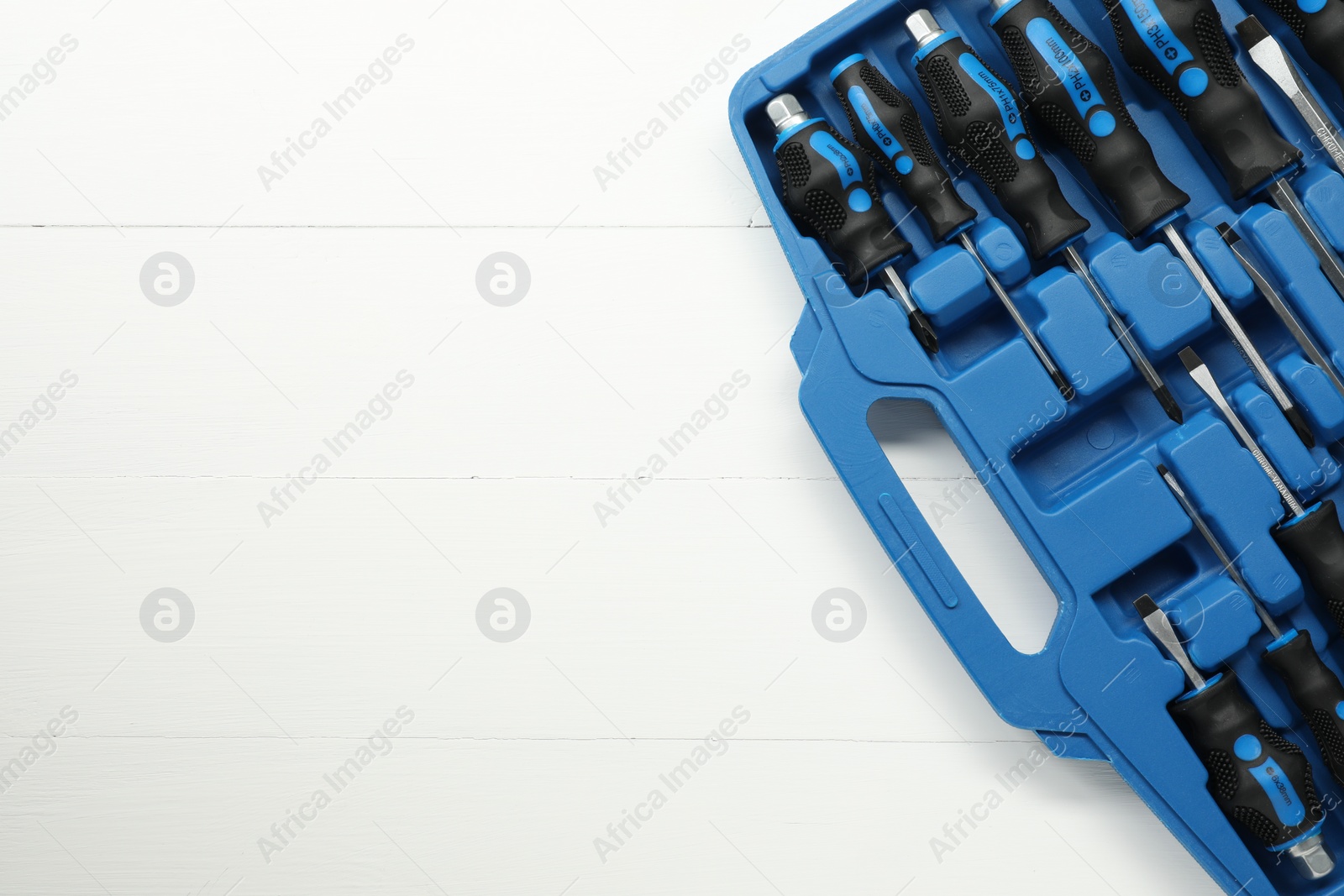 Photo of Set of screwdrivers in open toolbox on white wooden table, top view. Space for text
