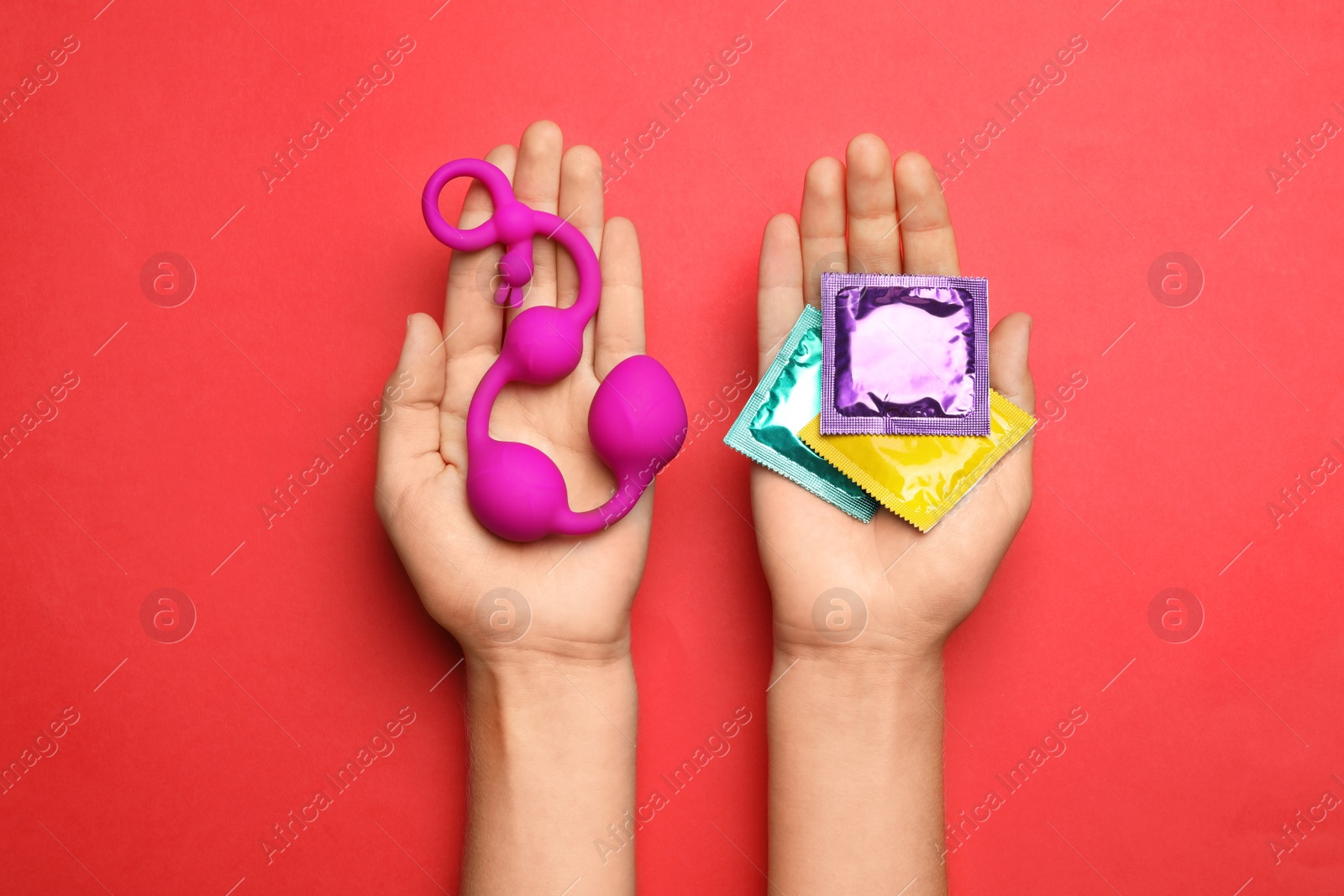 Photo of Woman with anal balls beads and condoms on red background, top view. Sex game