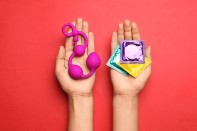 Woman with anal balls beads and condoms on red background, top view. Sex game