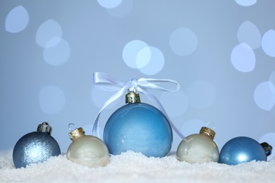 Beautiful Christmas balls on snow against blurred festive lights