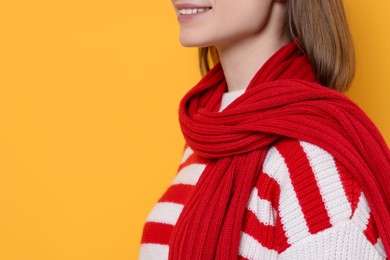 Photo of Beautiful woman in warm scarf on yellow background, closeup. Space for text