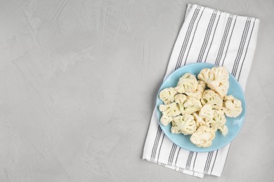 Plate with cut fresh raw cauliflower on light grey table, top view. Space for text