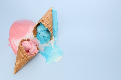 Melted ice cream in wafer cones on light blue background, above view. Space for text