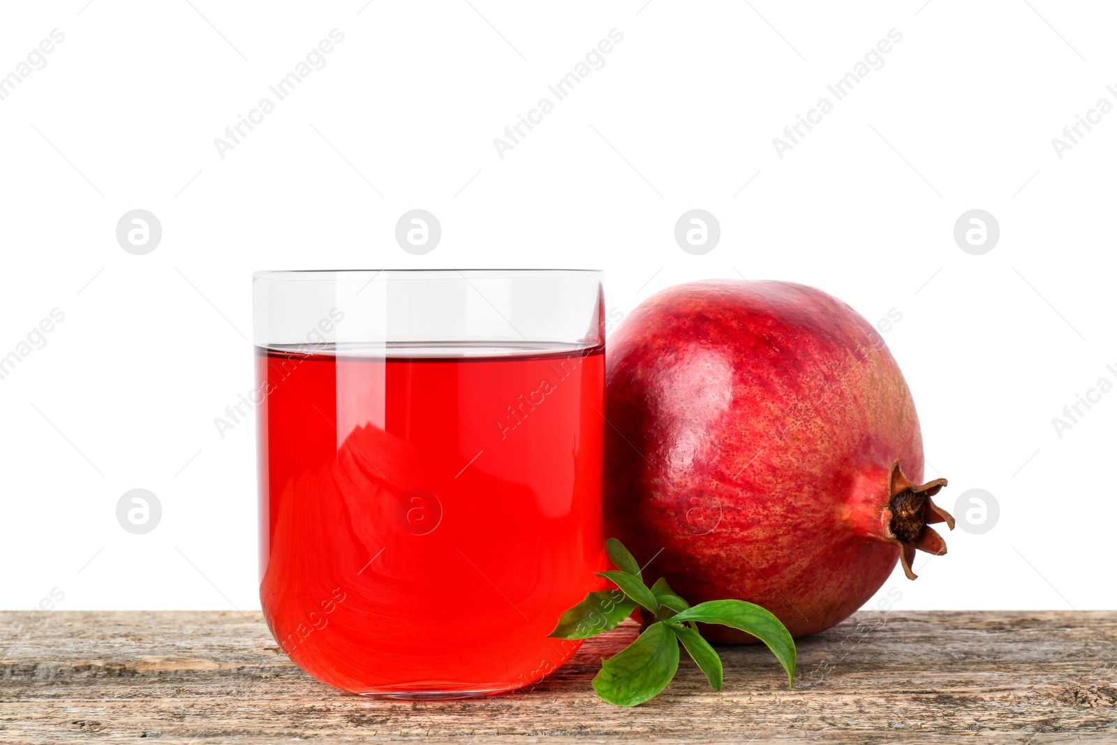 Photo of Refreshing pomegranate juice in glass, leaves and fruit on wooden table against white background