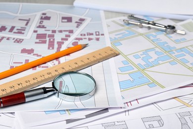 Photo of Office stationery and magnifying glass on cadastral maps of territory with buildings