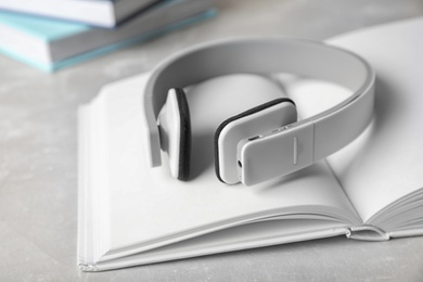 Photo of Modern headphones with hardcover book on grey background, closeup