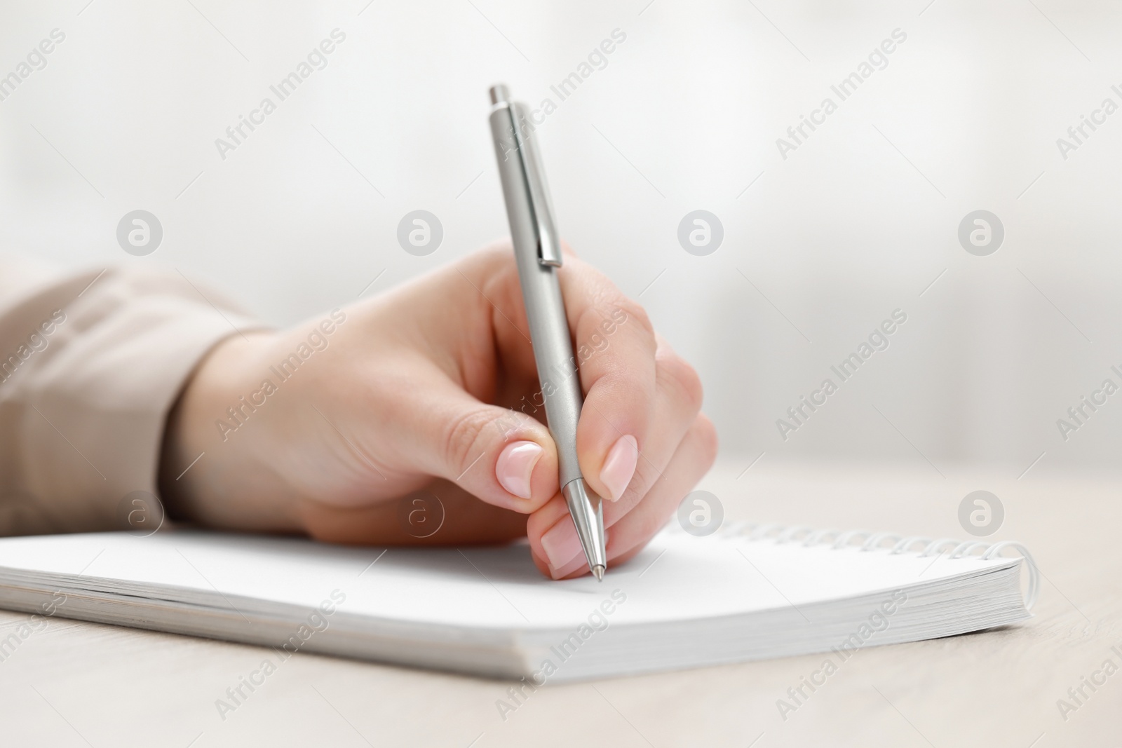 Photo of Woman writing in notebook at light table, closeup