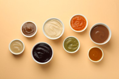 Photo of Bowls with healthy baby food on pale orange background, flat lay