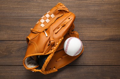 Photo of Leather baseball glove with ball on wooden table, top view
