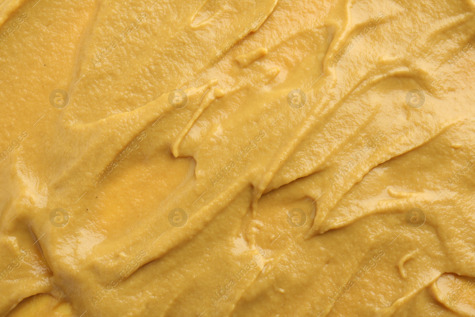 Photo of Fresh tasty mustard sauce as background, top view