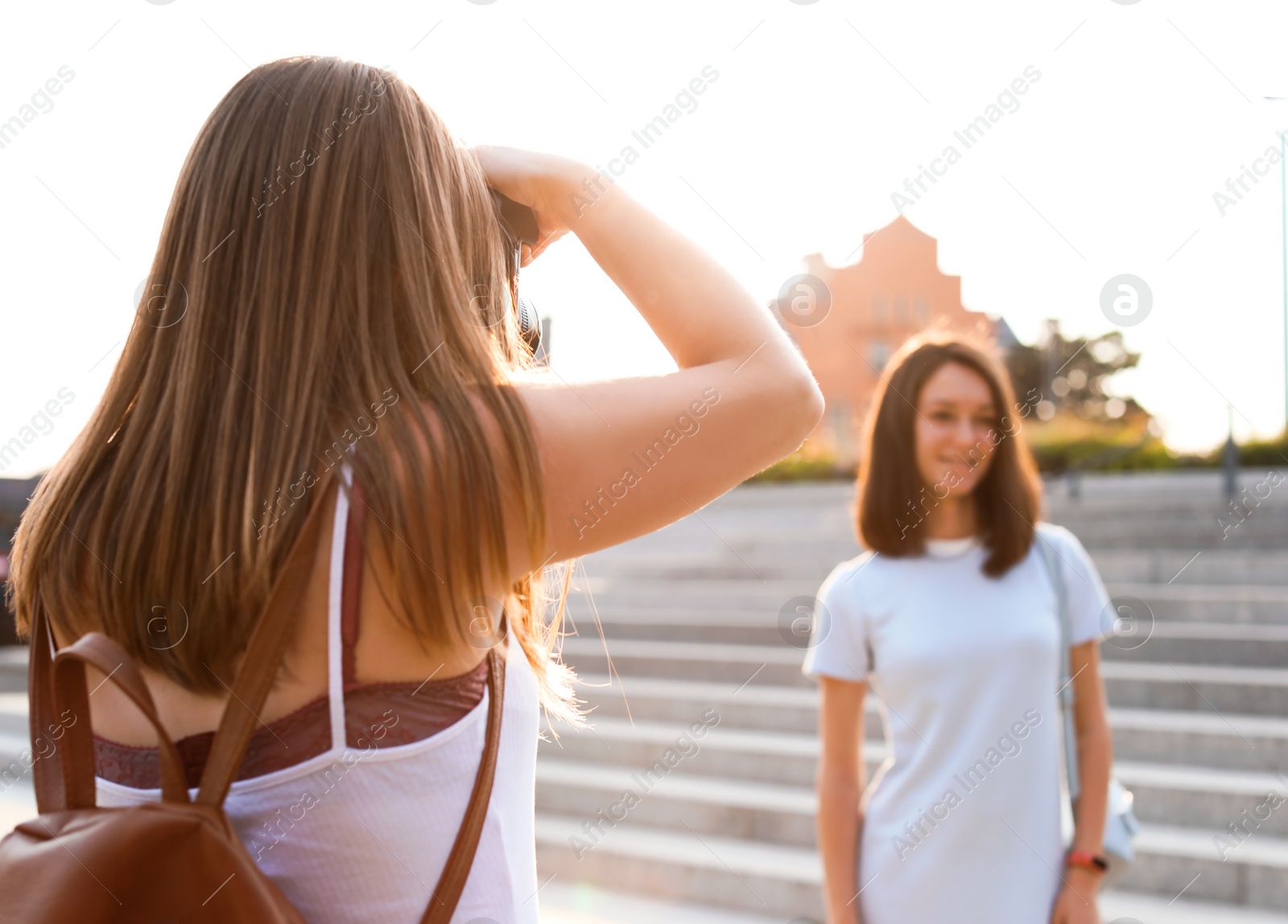 Photo of Young woman taking photo of her friend outdoors