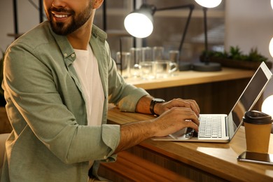 Photo of Man working with laptop at table in cafe, closeup