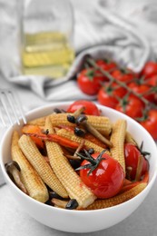 Tasty roasted baby corn with tomatoes and mushrooms on light grey table, closeup