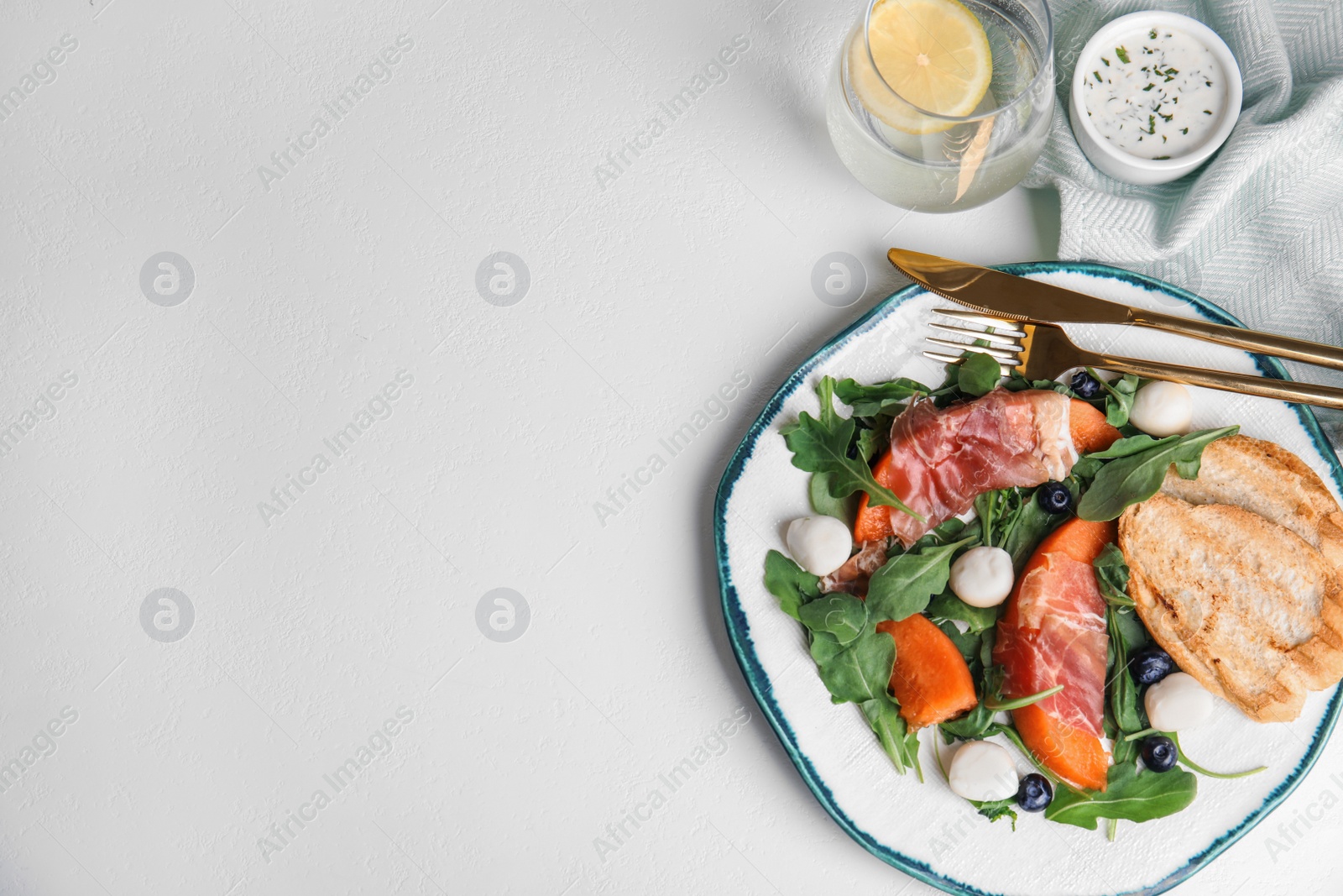 Photo of Flat lay composition of fresh melon with prosciutto on white table. Space for text