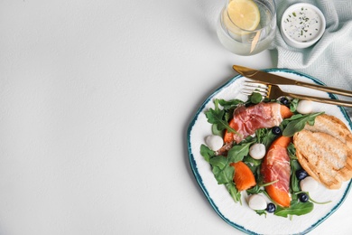 Photo of Flat lay composition of fresh melon with prosciutto on white table. Space for text