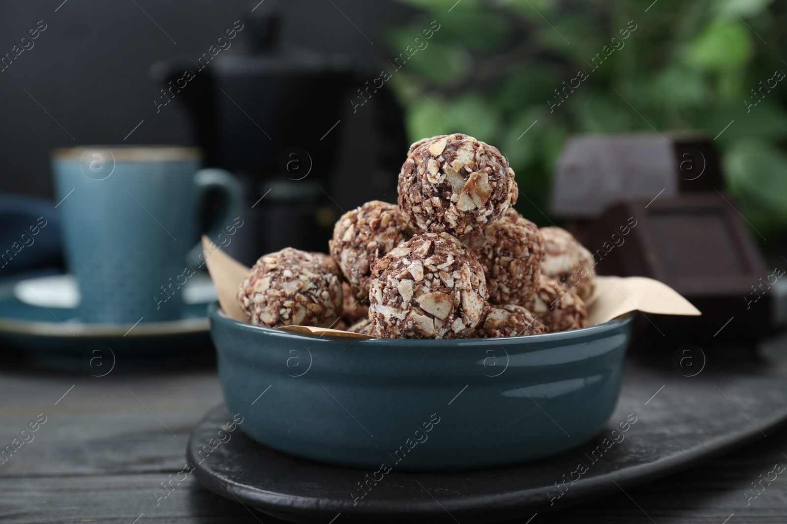 Photo of Bowl of delicious sweet chocolate candies on black table, closeup