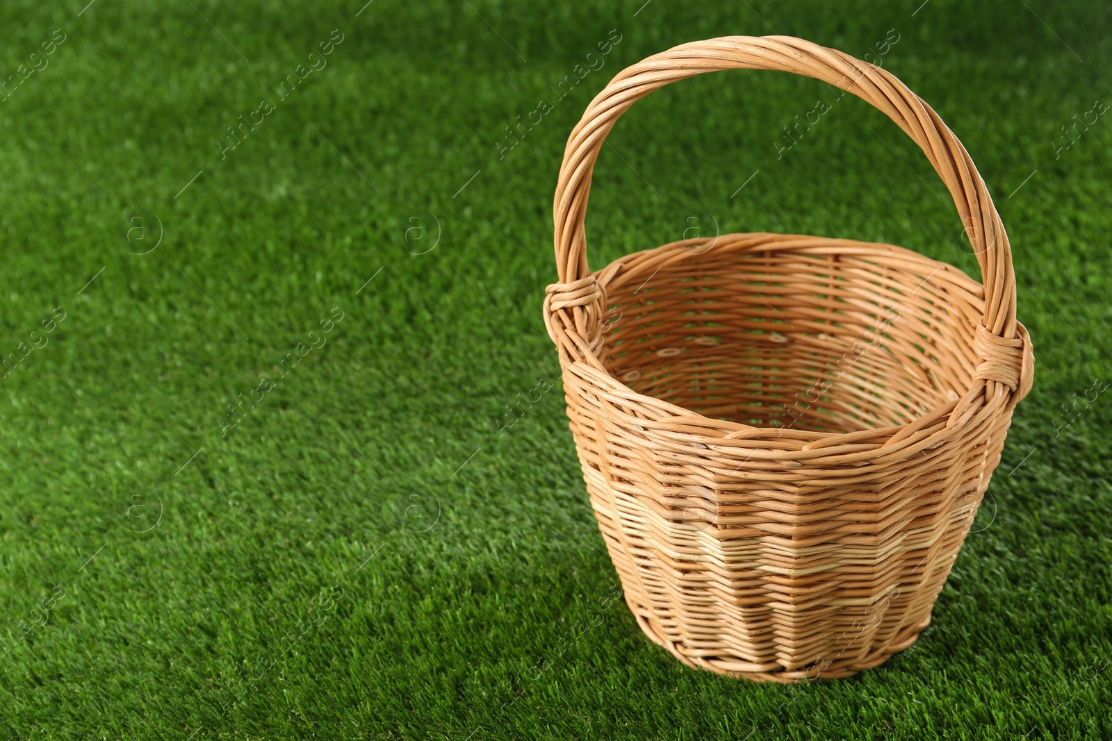 Photo of Empty wicker basket on green lawn, space for text. Easter item