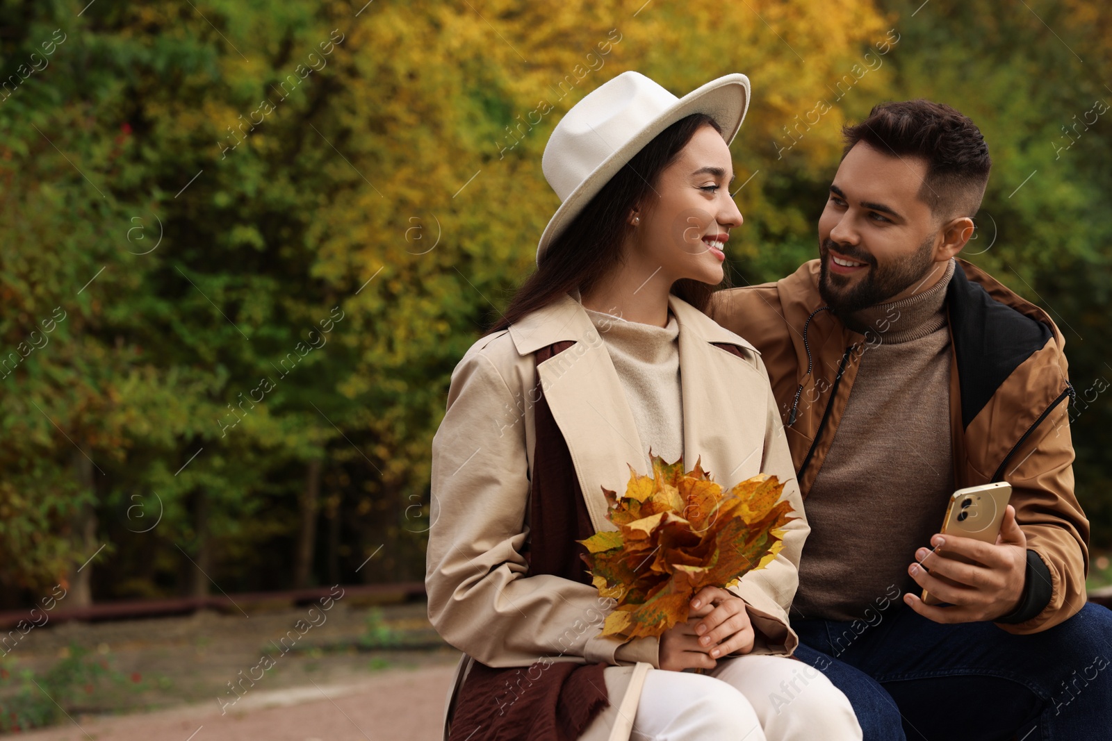 Photo of Romantic young couple spending time together in autumn park, space for text