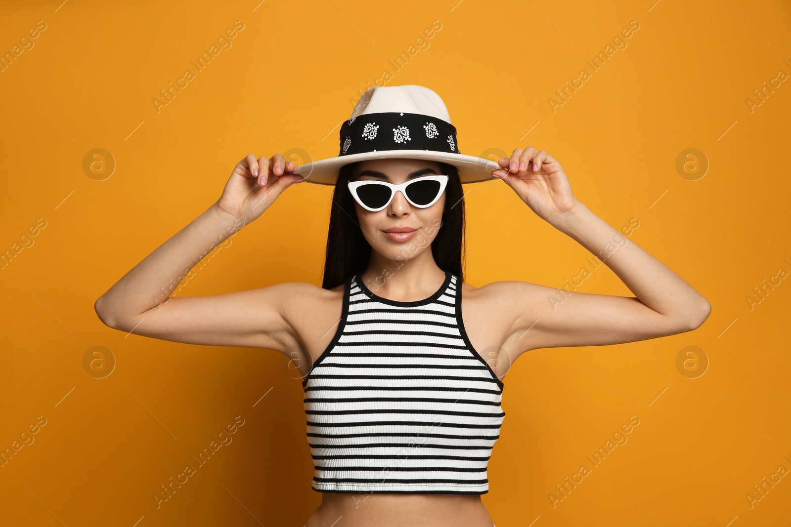 Photo of Fashionable young woman in stylish outfit with bandana on orange background