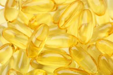 Photo of Yellow vitamin capsules as background, top view