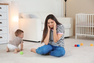 Young mother suffering from postnatal depression and cute baby boy at home