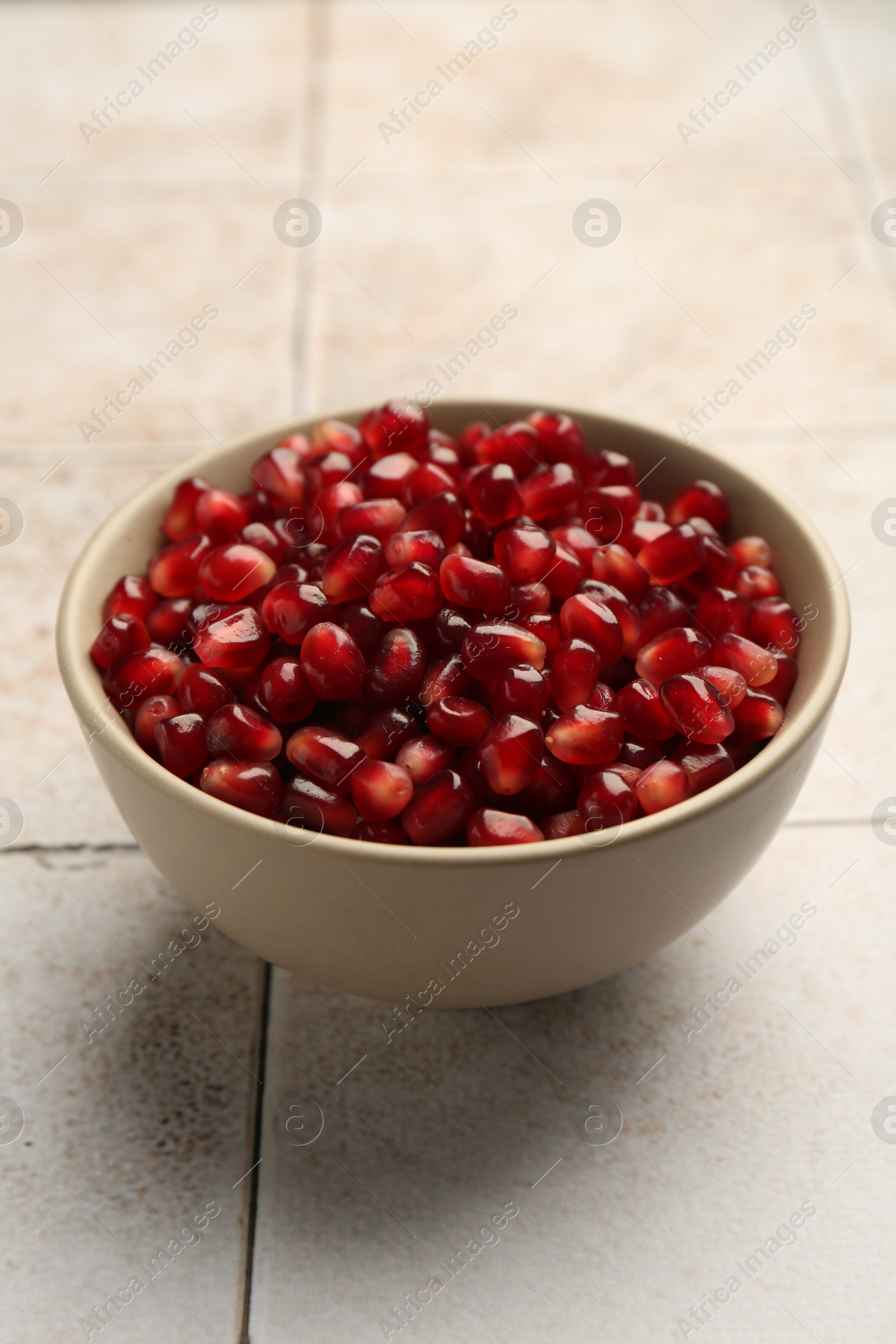 Photo of Tasty ripe pomegranate grains on tiled table