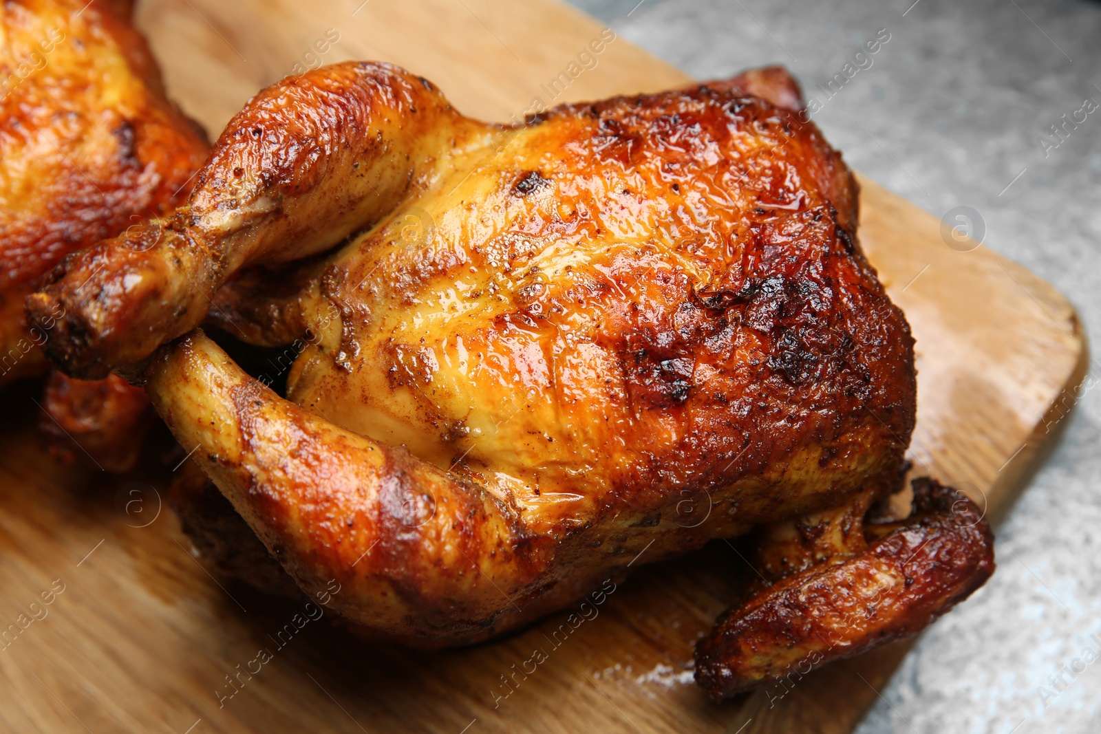 Photo of Delicious grilled whole chickens on grey table, closeup