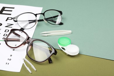 Photo of Vision test chart, glasses, lenses and tweezers on color background, closeup. Space for text