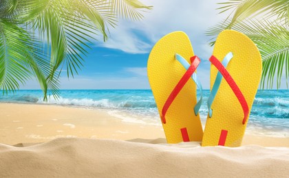 Image of Yellow flip flops  on sandy beach near sea 