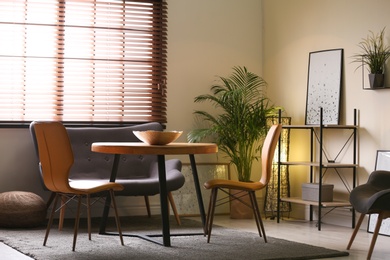 Photo of Stylish dining room interior with modern table set and window blinds