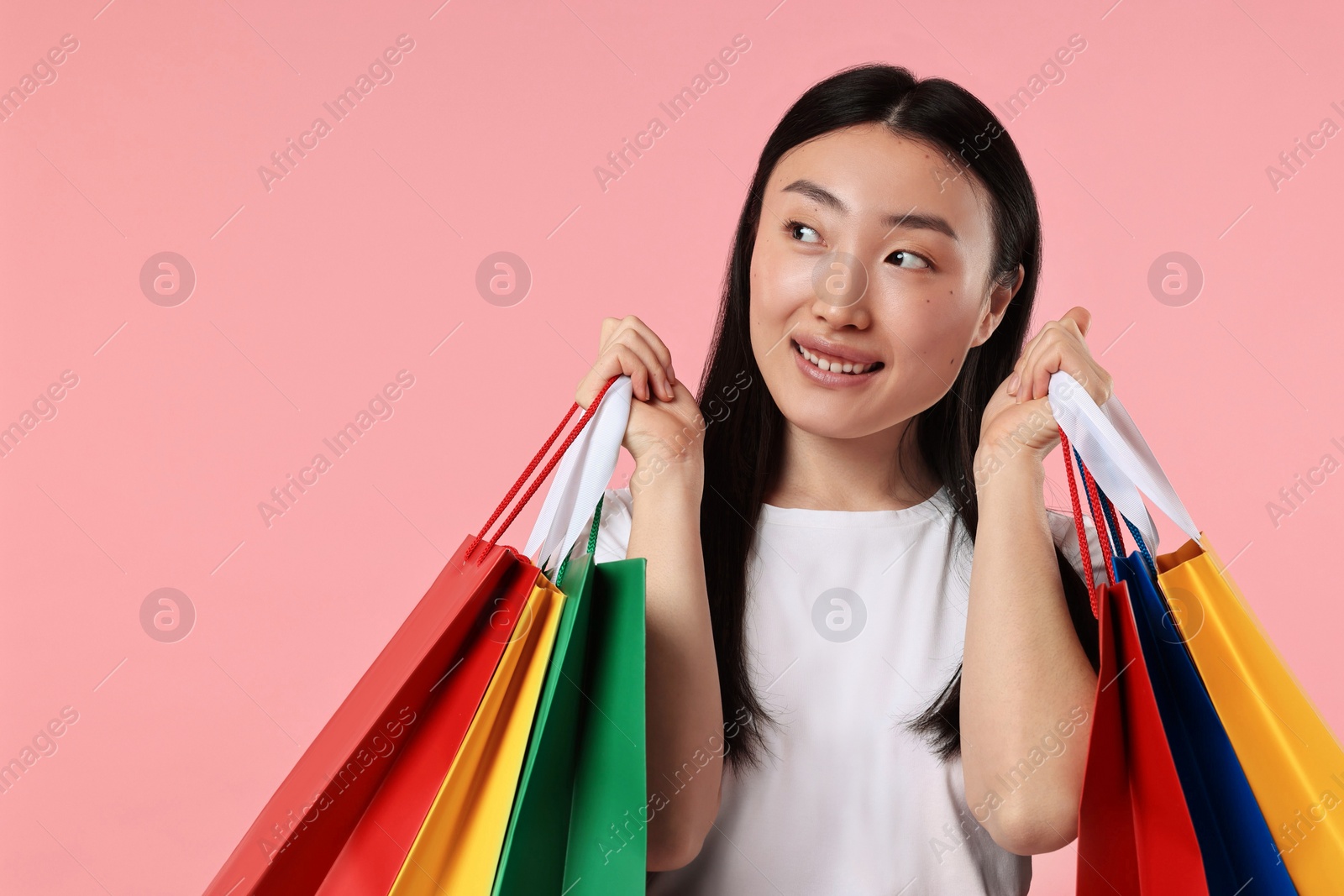 Photo of Smiling woman with shopping bags on pink background. Space for text