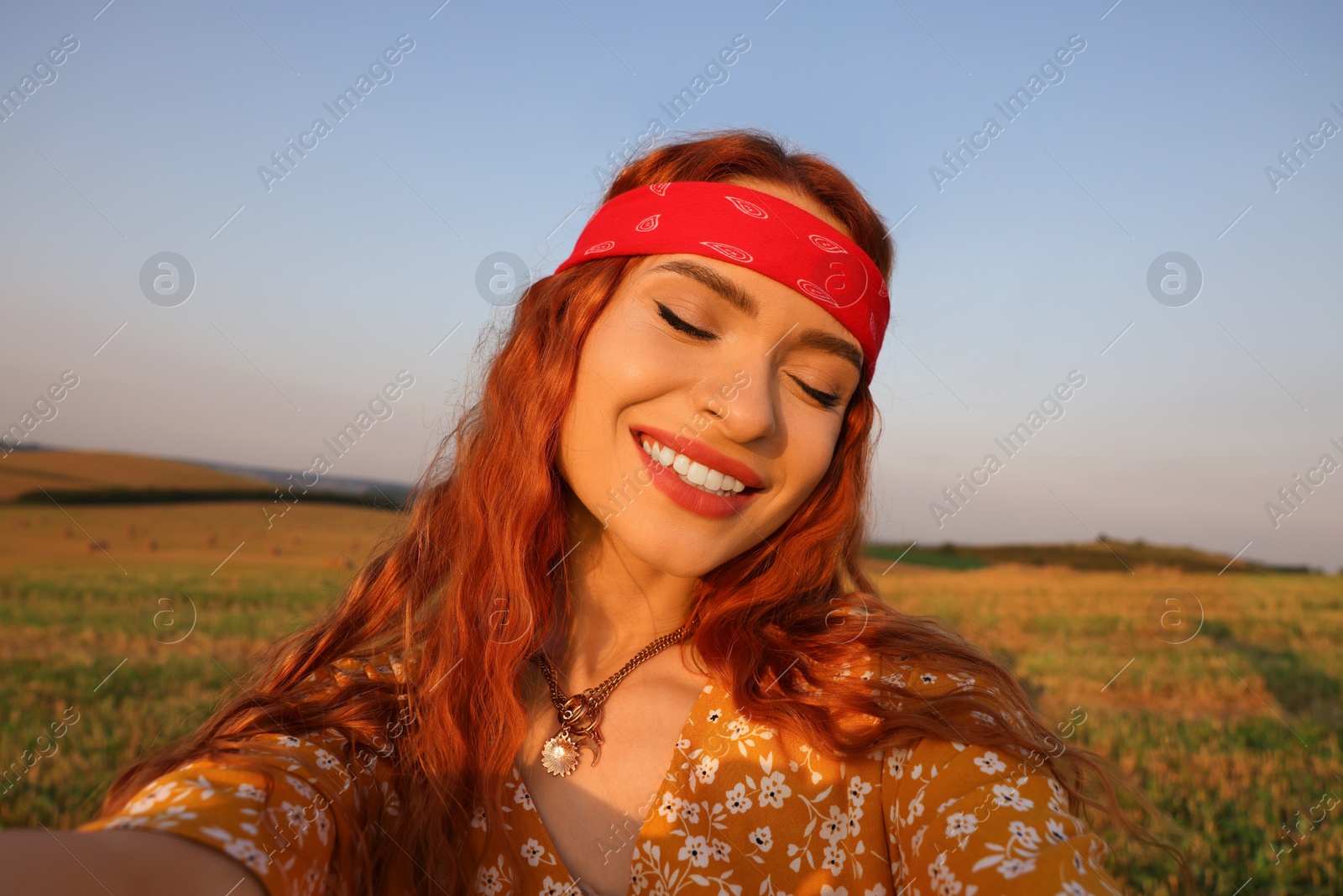 Photo of Beautiful happy hippie woman taking selfie in field