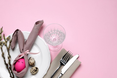 Festive Easter table setting with eggs on pink background, flat lay