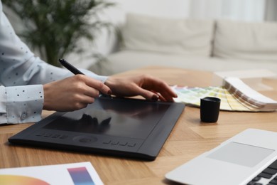 Professional designer with graphic tablet at wooden table, closeup