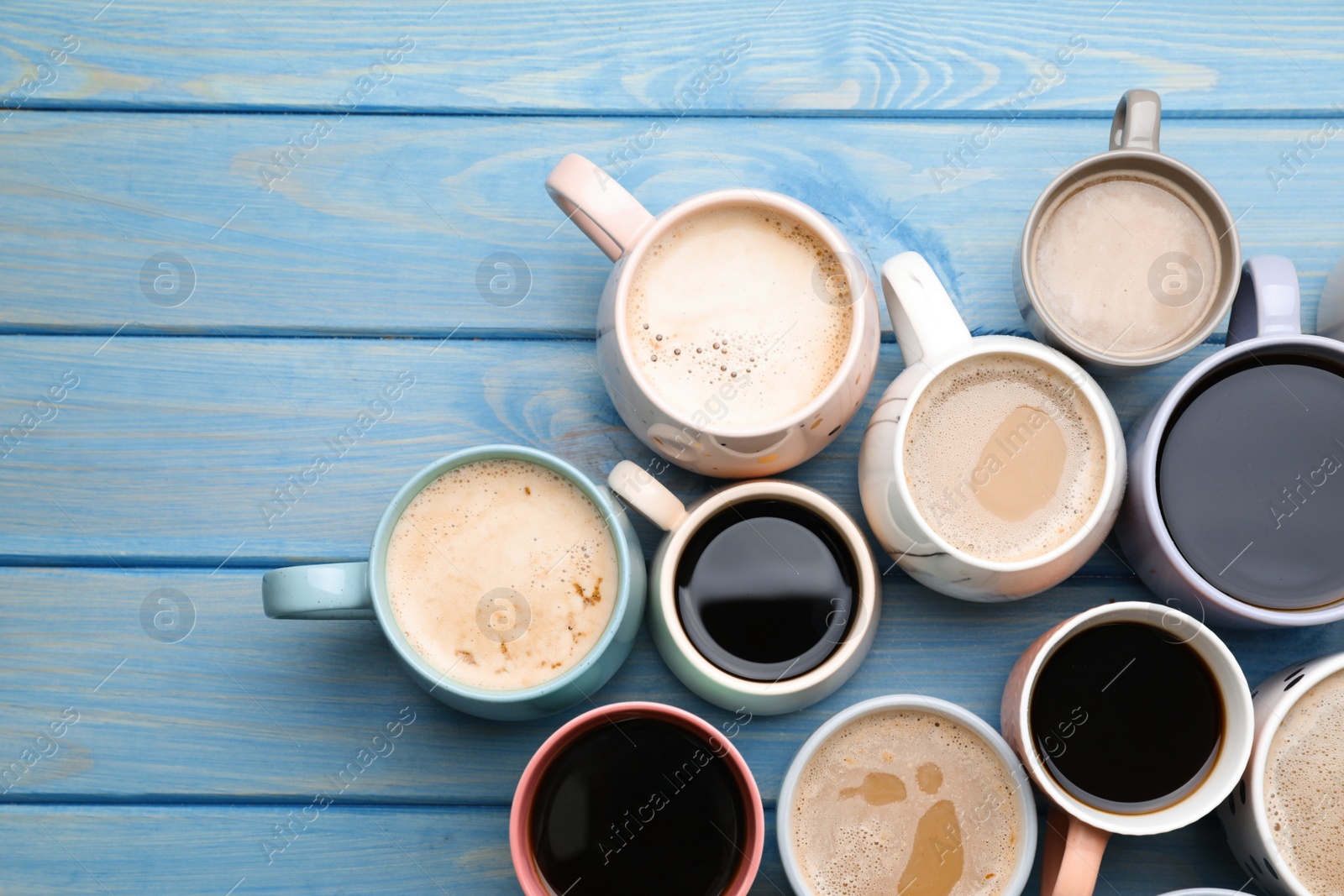 Photo of Many cups of different coffee drinks on light blue wooden table, flat lay