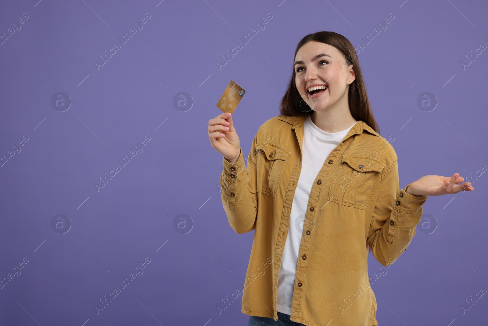 Photo of Happy woman with credit card on purple background, space for text