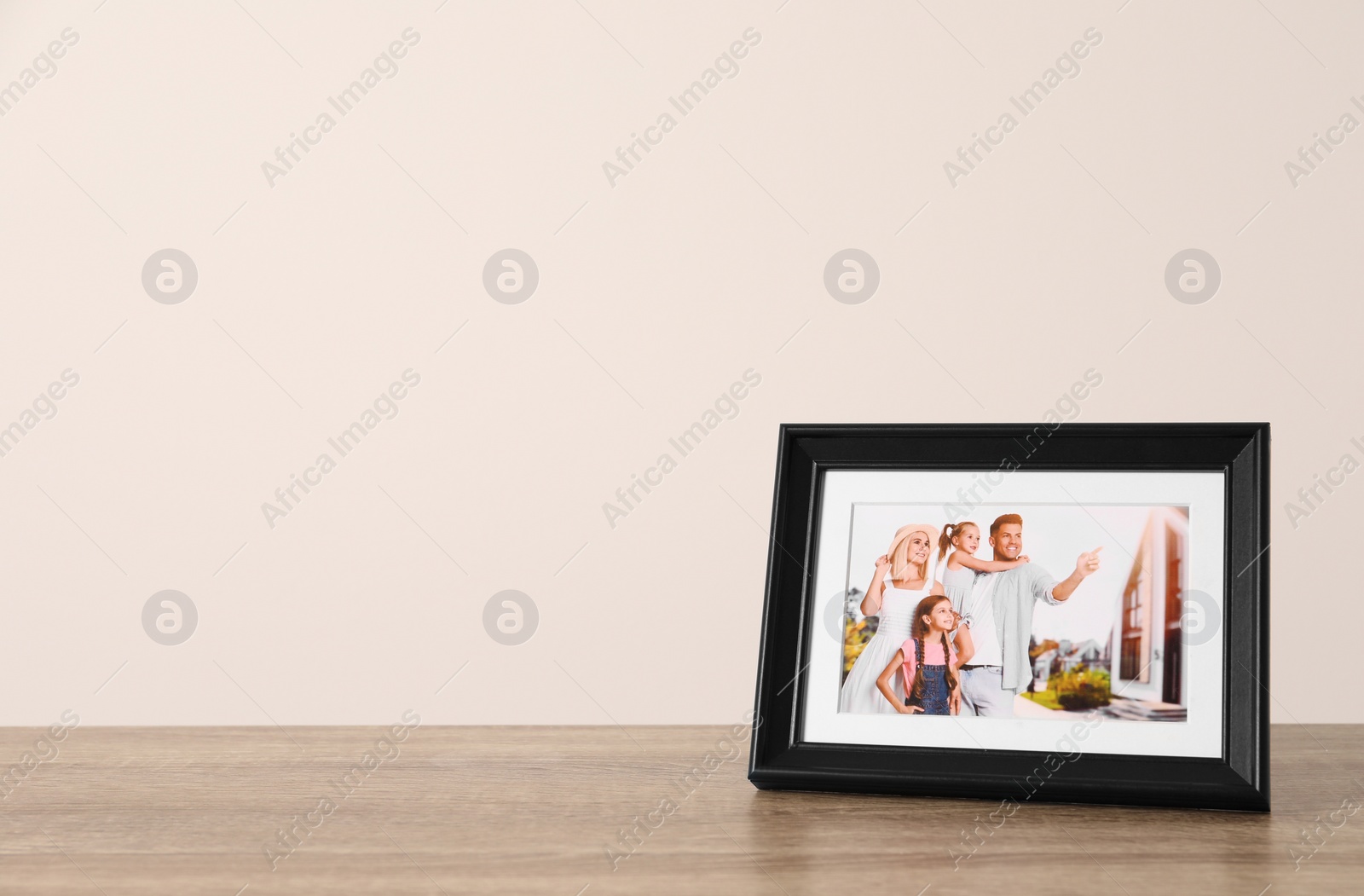 Photo of Frame with family photo on wooden table, space for text