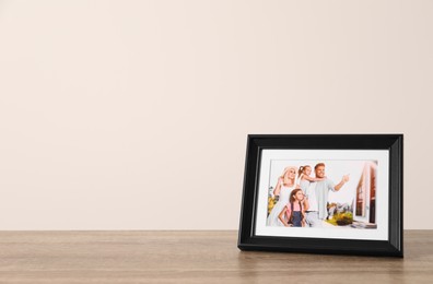 Frame with family photo on wooden table, space for text