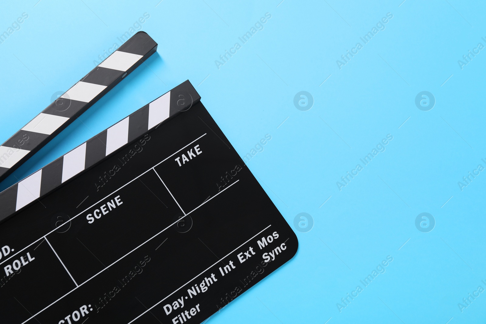 Photo of Clapperboard on light blue background, top view. Space for text
